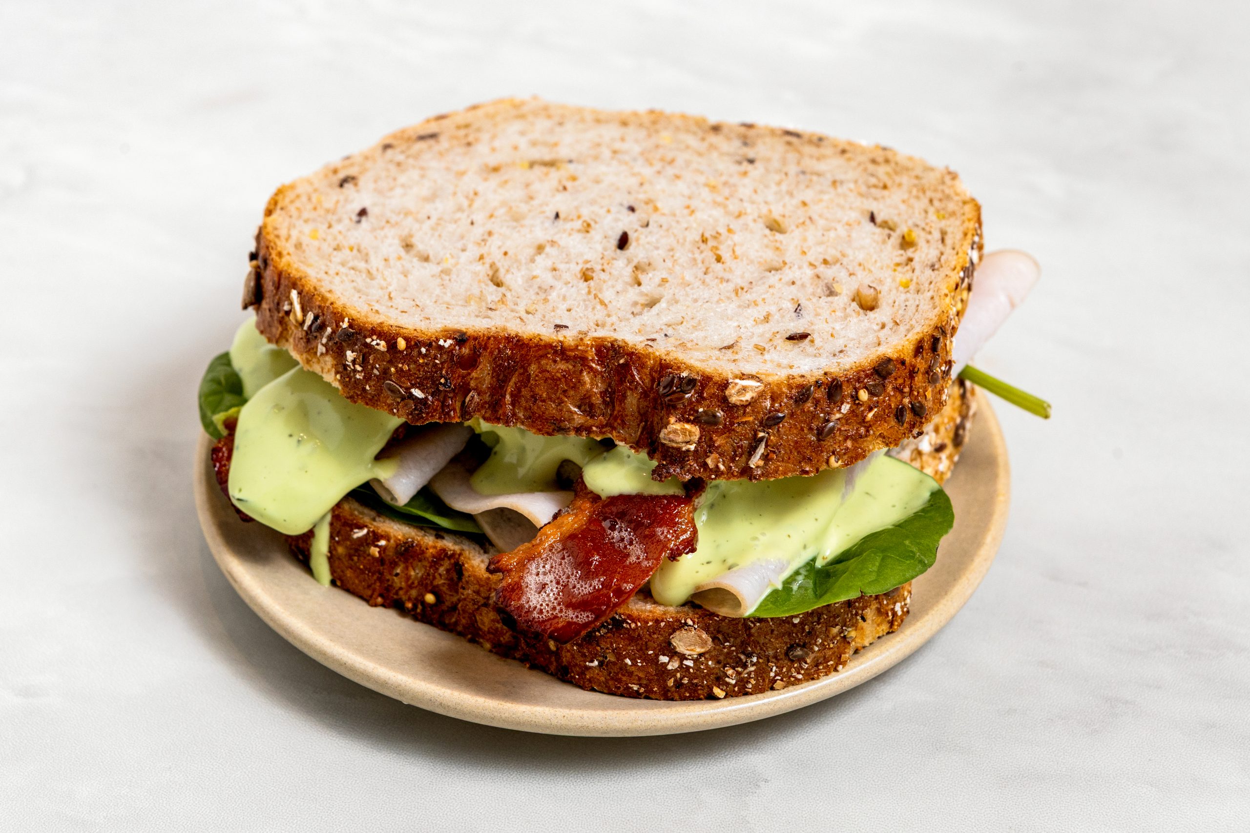 Turkey Bacon Avocado Sandwich - Smoked Turkey, Crisp Bacon, Smashed Avocado & Green Goddess Spread on Whole Grain